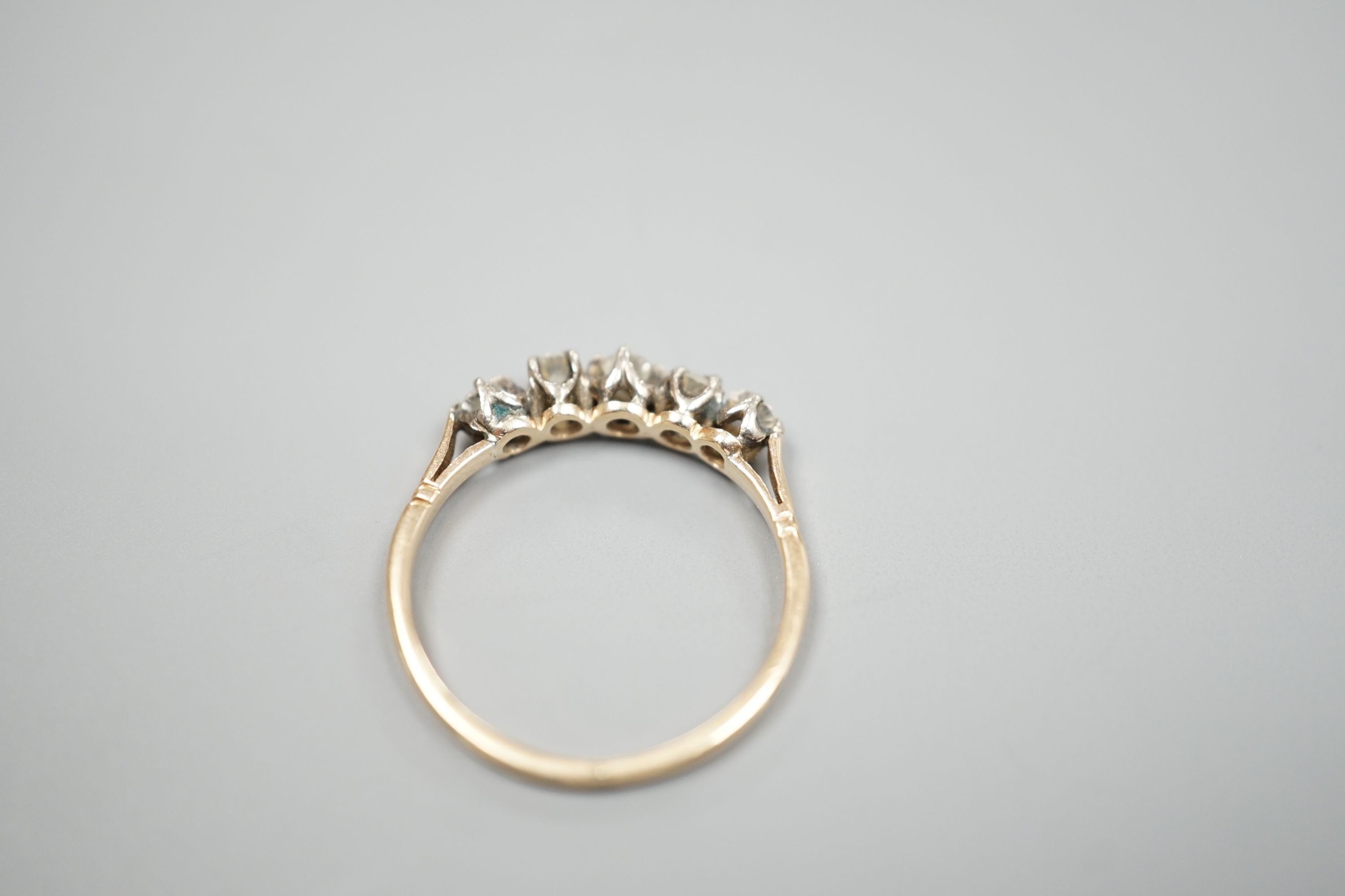 A yellow metal and five stone diamond set half hoop ring, size M, gross weight 1.6 grams.